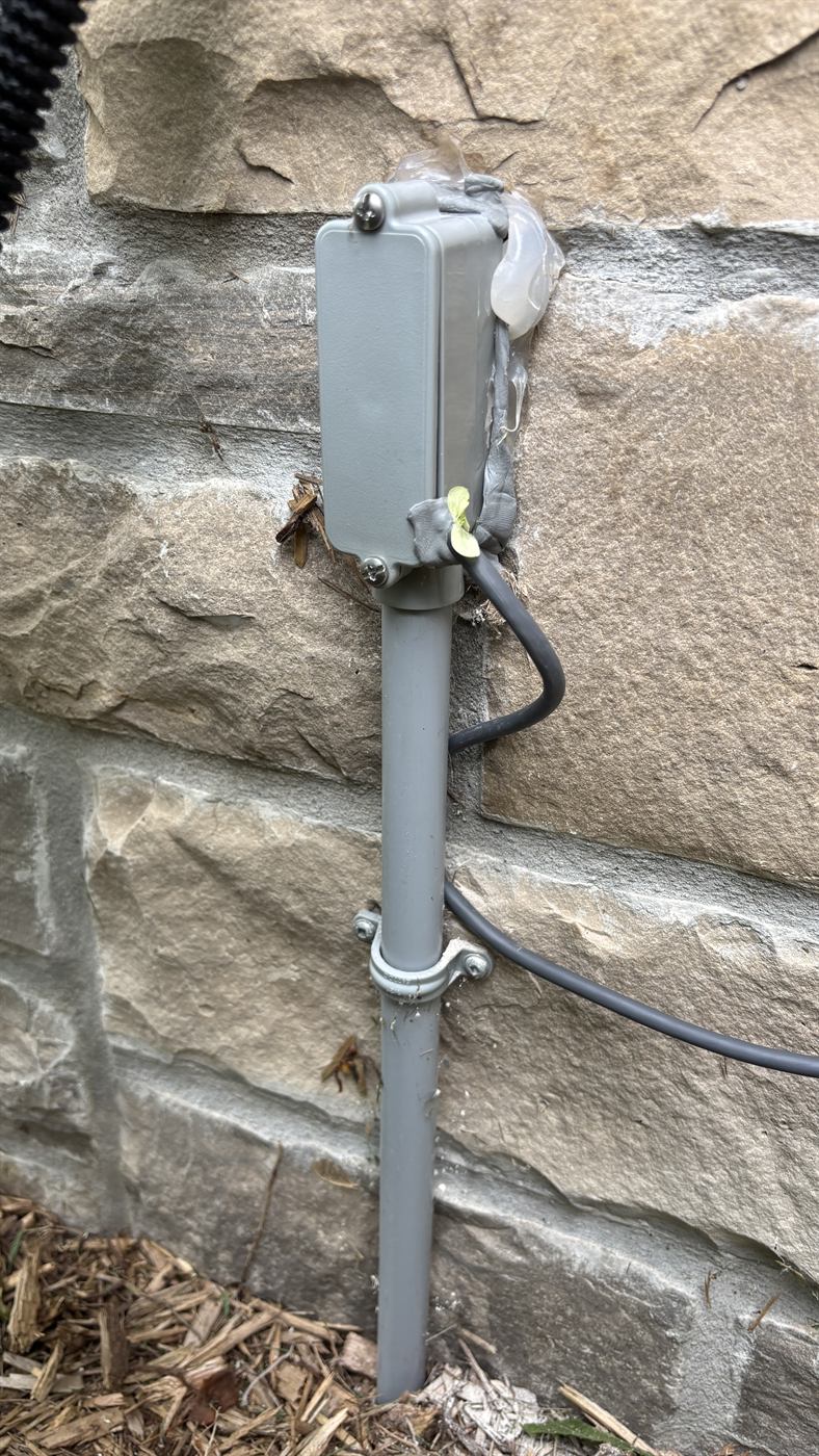 Weatherproof junction box and conduit at the stone wall entry point
